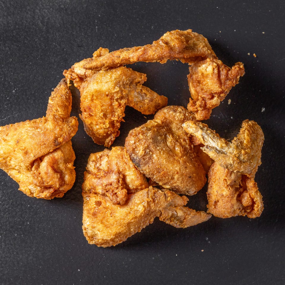 Crispy golden fried chicken pieces arranged on a dark surface.