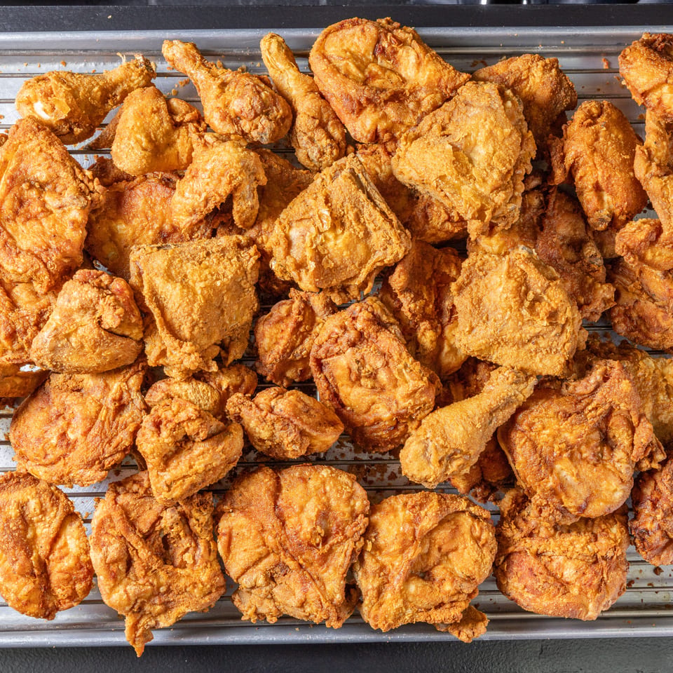 Crispy golden fried chicken pieces arranged across a wire rack over a metal baking sheet.